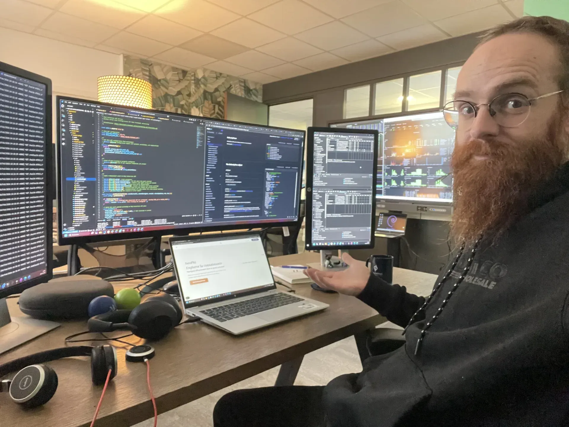 Pierre Holat sur son poste multi-écrans affichant du code et l’application NeoPhi